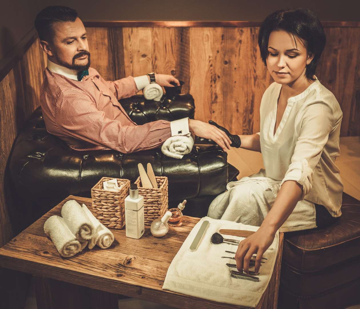 Confident old-fashioned man doing male manicure in a barber shop.