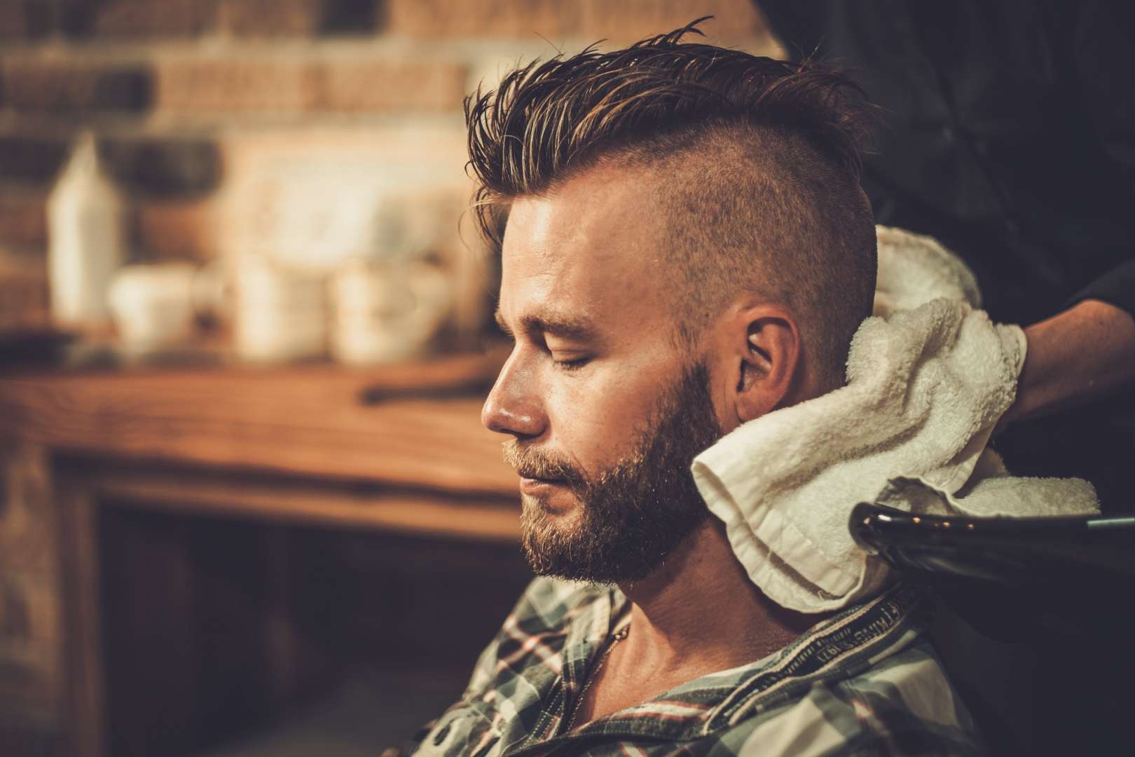 Hairstylist washing client's hair in barber shop