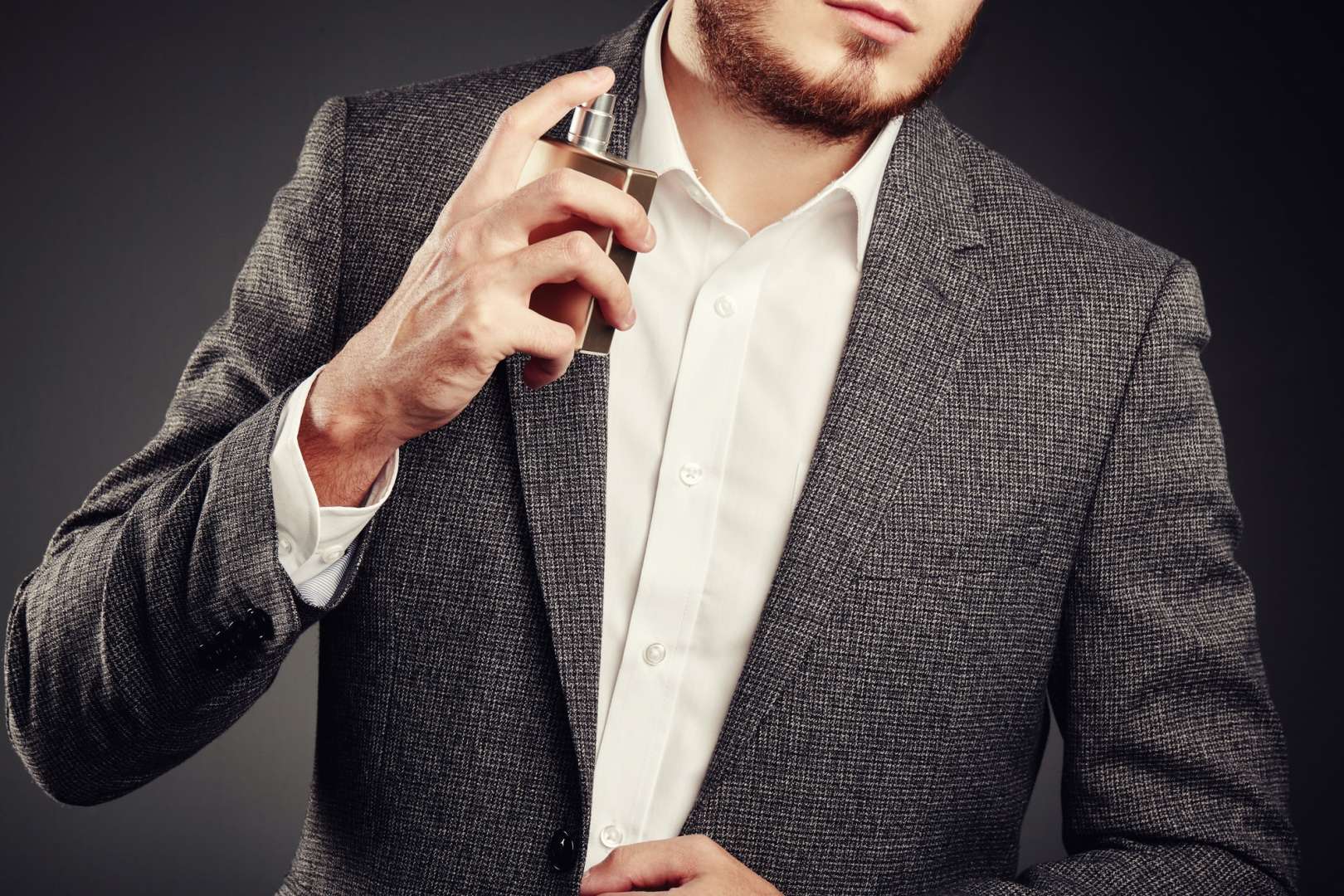 Handsome young man using perfume