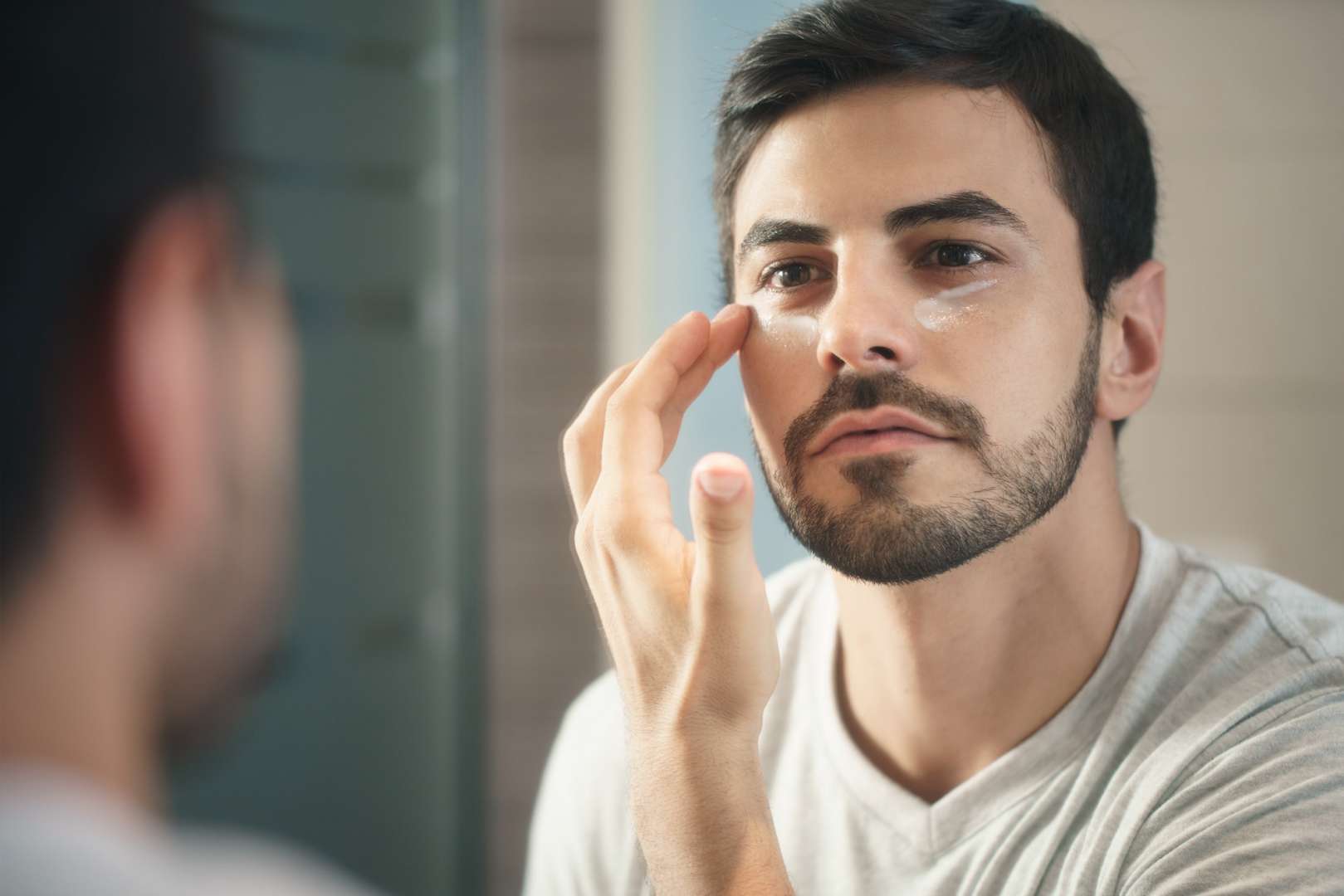 Young Man Applying Anti-aging Lotion fot Skin Care