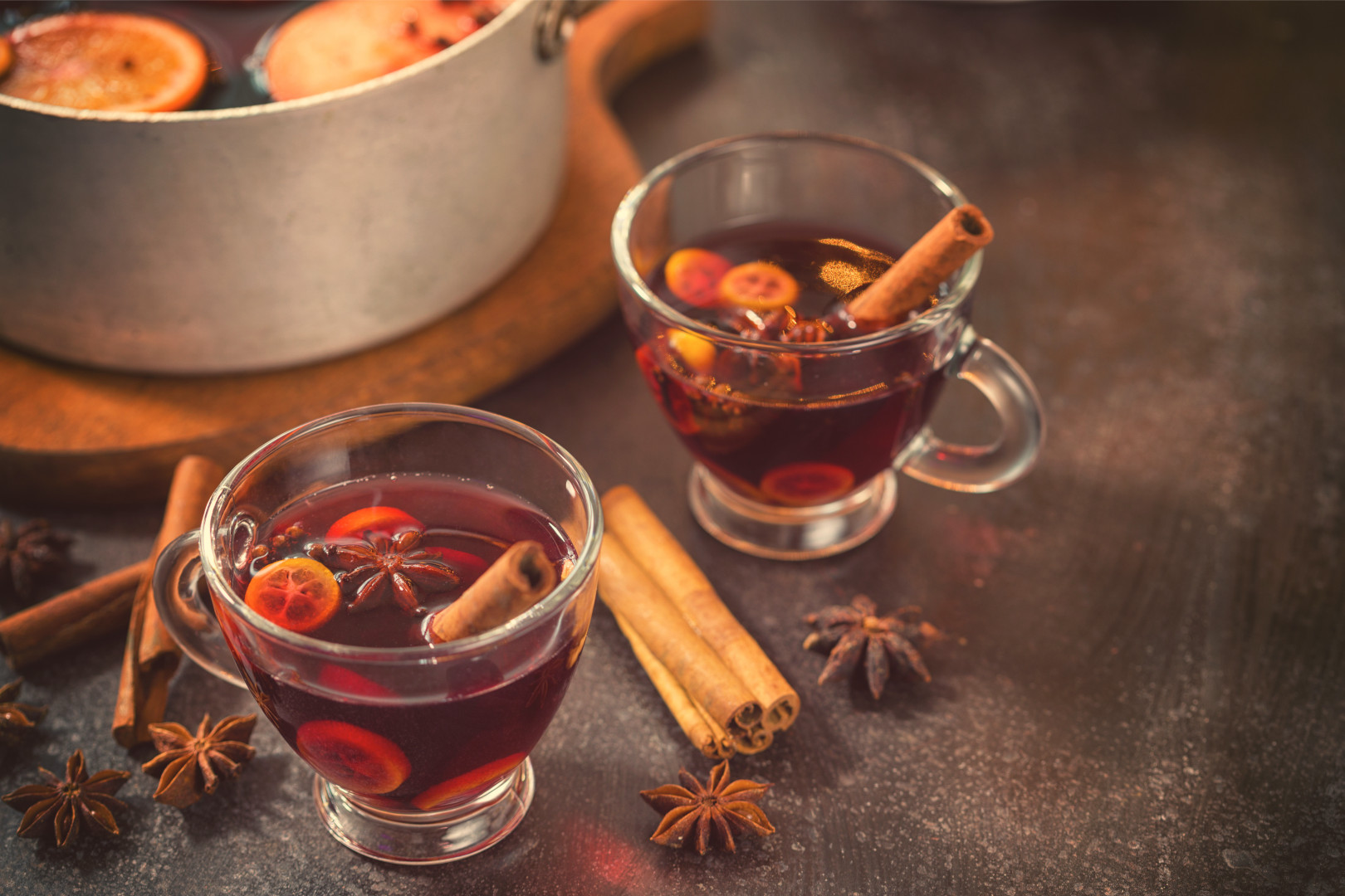 Two mugs of mulled wine sitting on a counter next to a pot