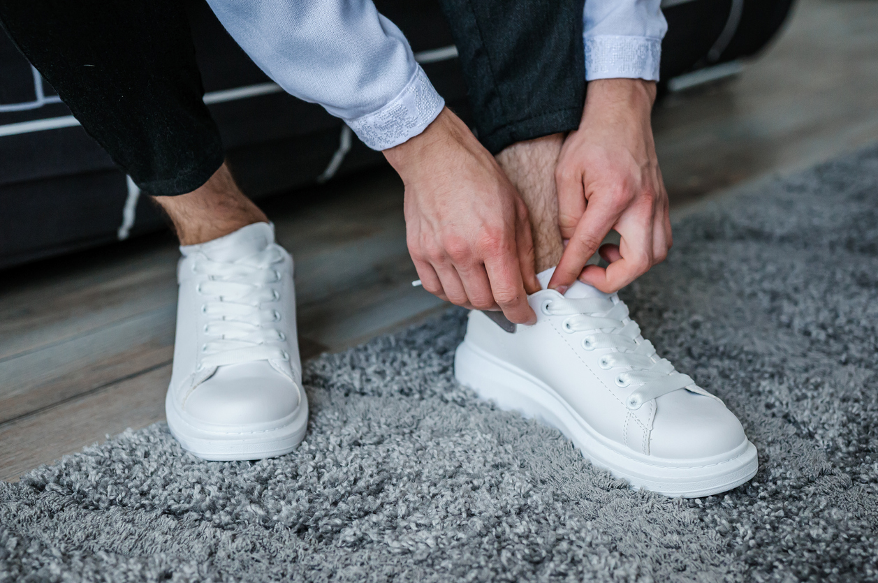 Man lacing a pair of plain white low-stop sneakers