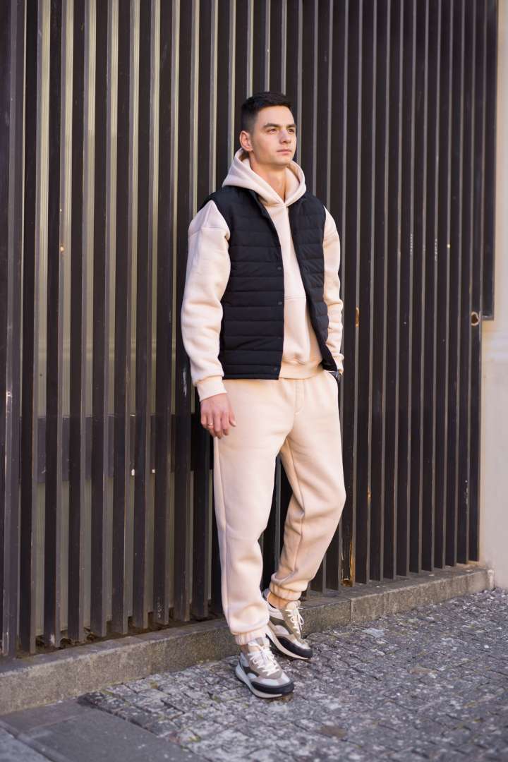 Young man in a matching sweatsuit with a puffer vest and athletic shoes