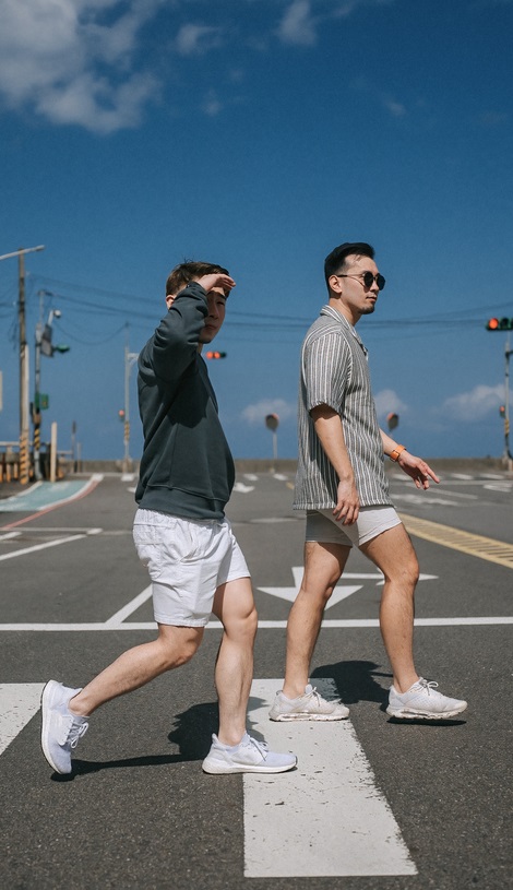 Two Chinese men in shorts above the knee walk through a crosswalk