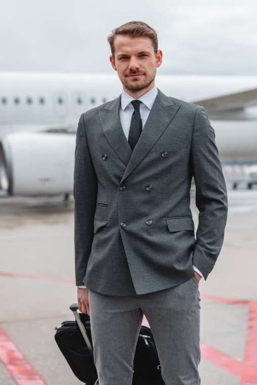 Man in a double-breasted suit jacket standing in front of a plane