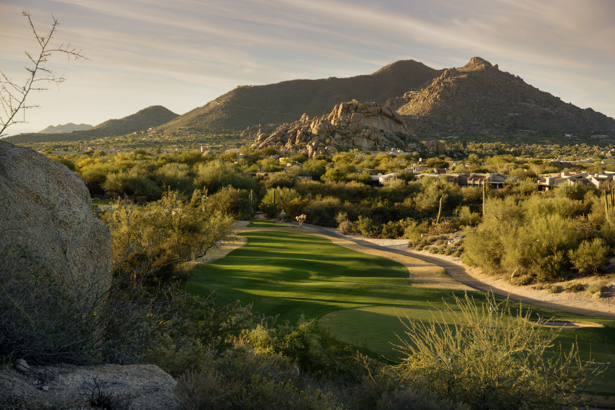 Golden hour Arizona landscape showing golf course, greenery, and mountains 