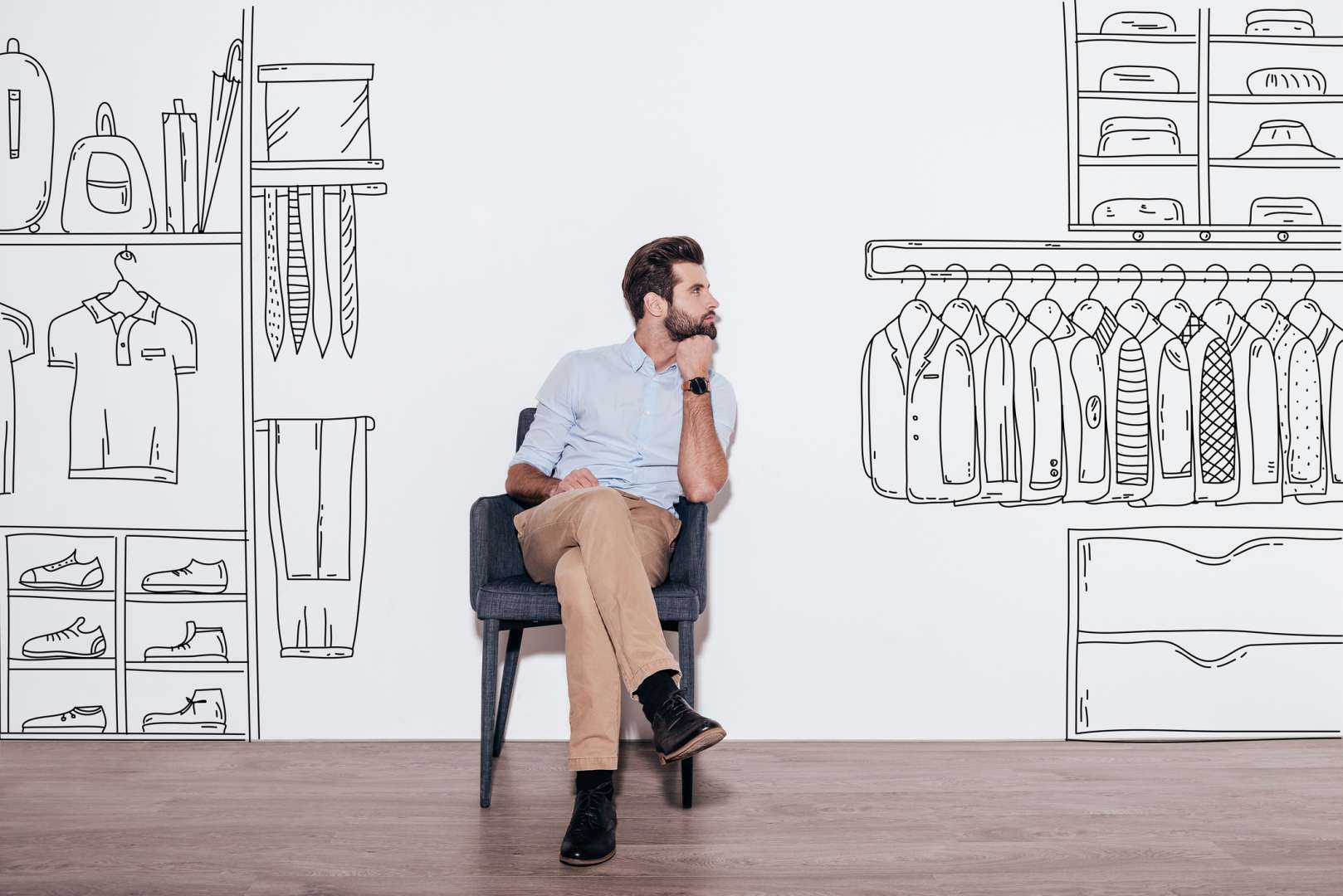 Young man sitting in a chair against a backdrop of an illustrated closet