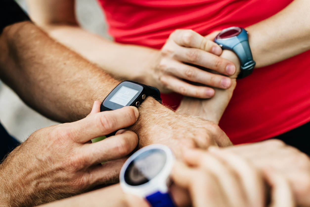 A close up of a group of amateur athletes synchronizing their smart watches together before setting off on their weekly run in the city